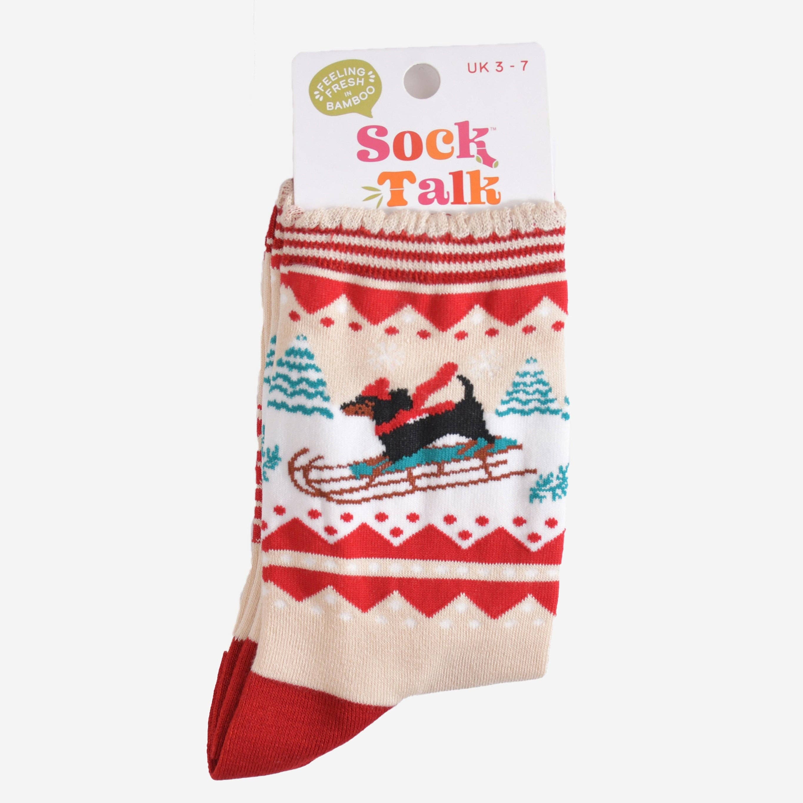 Et par kremfargede bambussokker med røde detaljer og dachshunddesign i sin originale emballasje med merkets navn "Sock Talk".